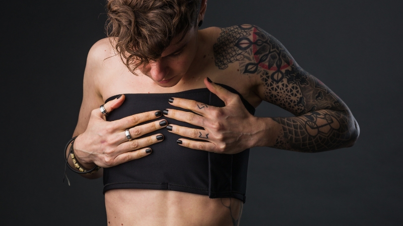 A person adjusting a chest binder while focusing on binding safely for comfort and proper fit