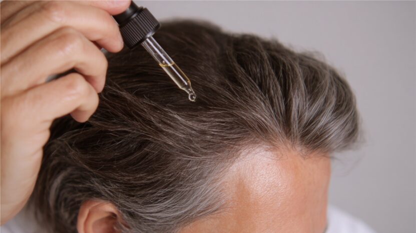 Close-up of a person applying peptide serum to their scalp with a dropper