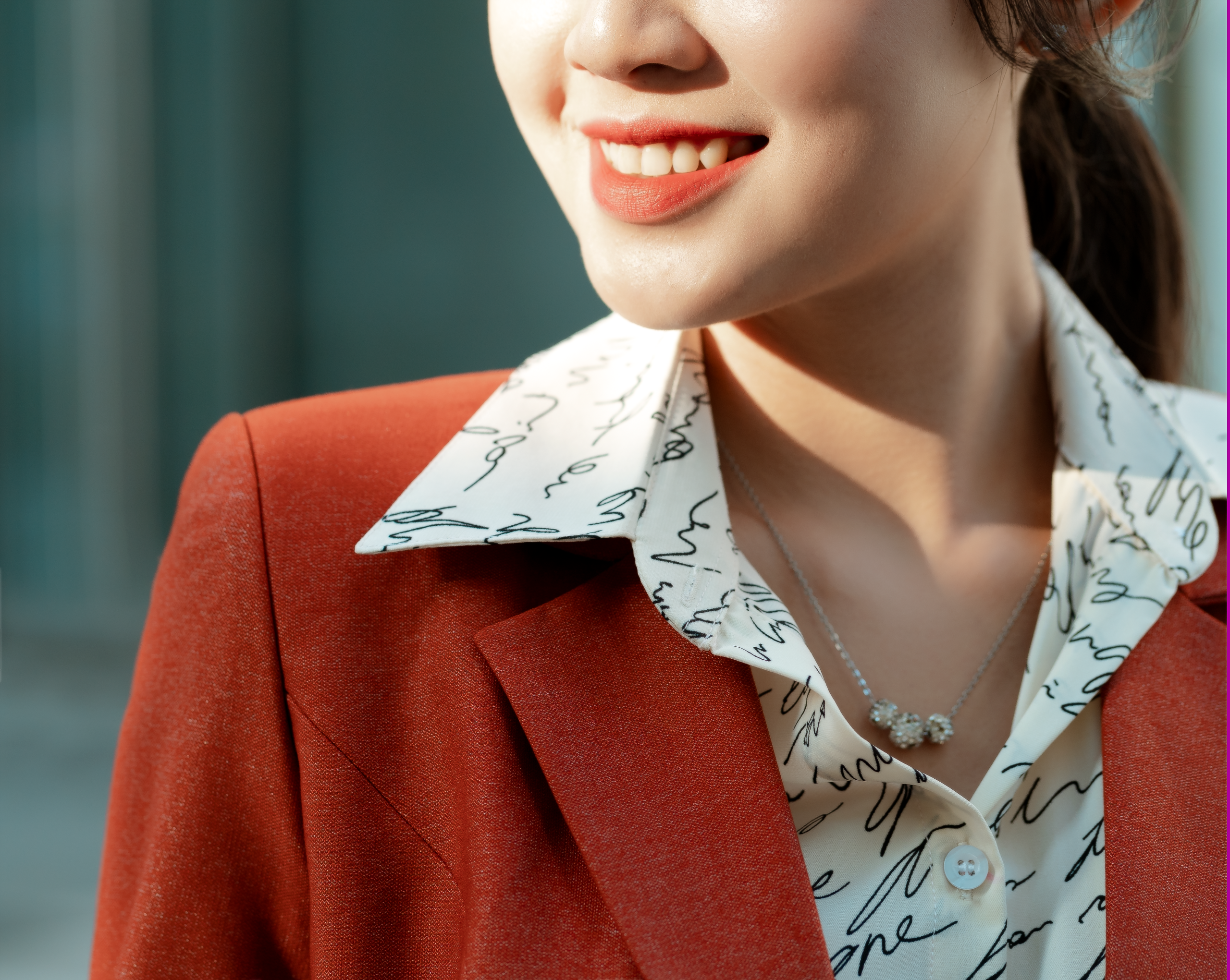 Confident woman in a red blazer wearing a necklace, illustrating polished personal style.