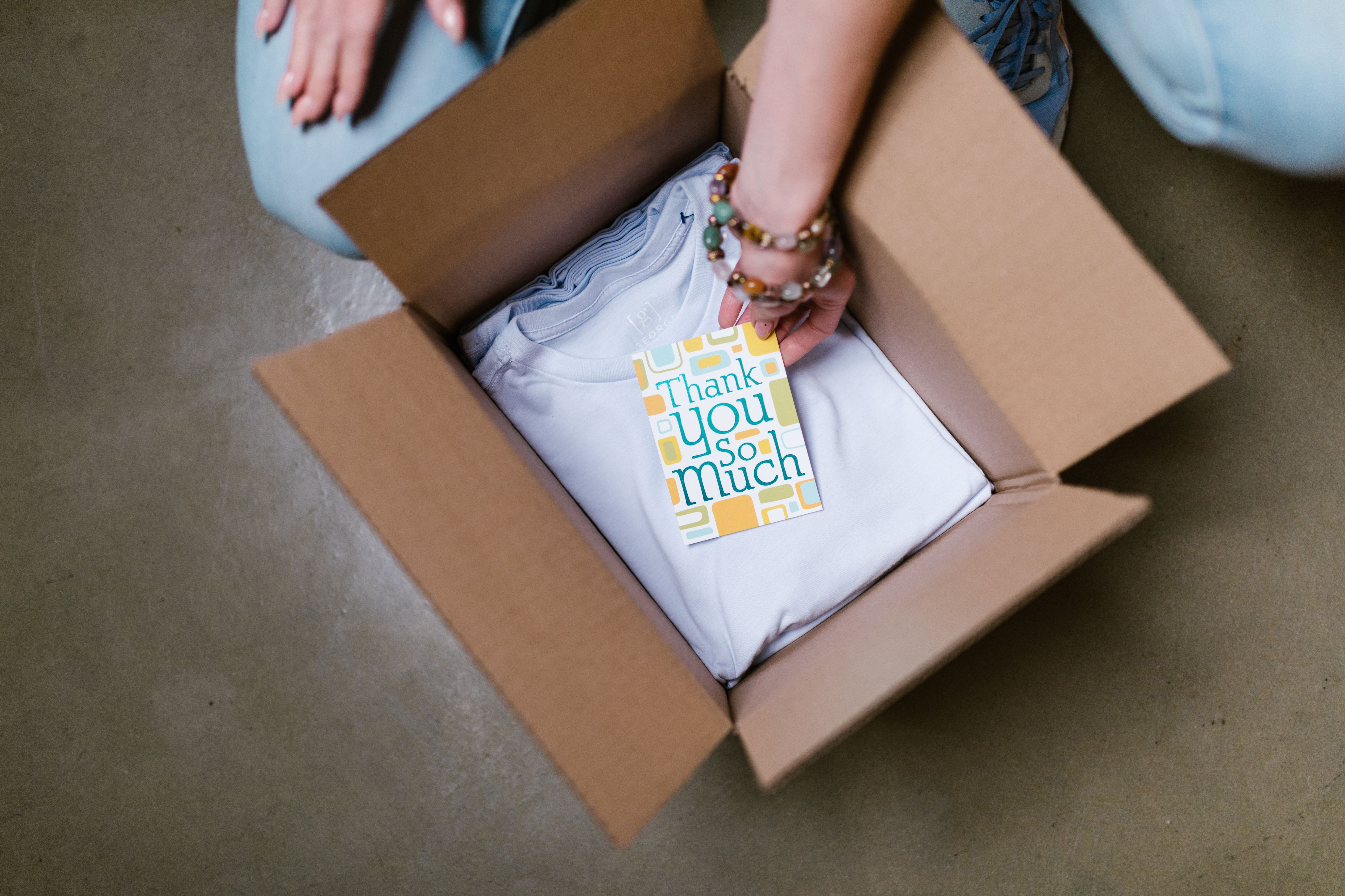 Small business owner packing a T-shirt order with a thank-you card