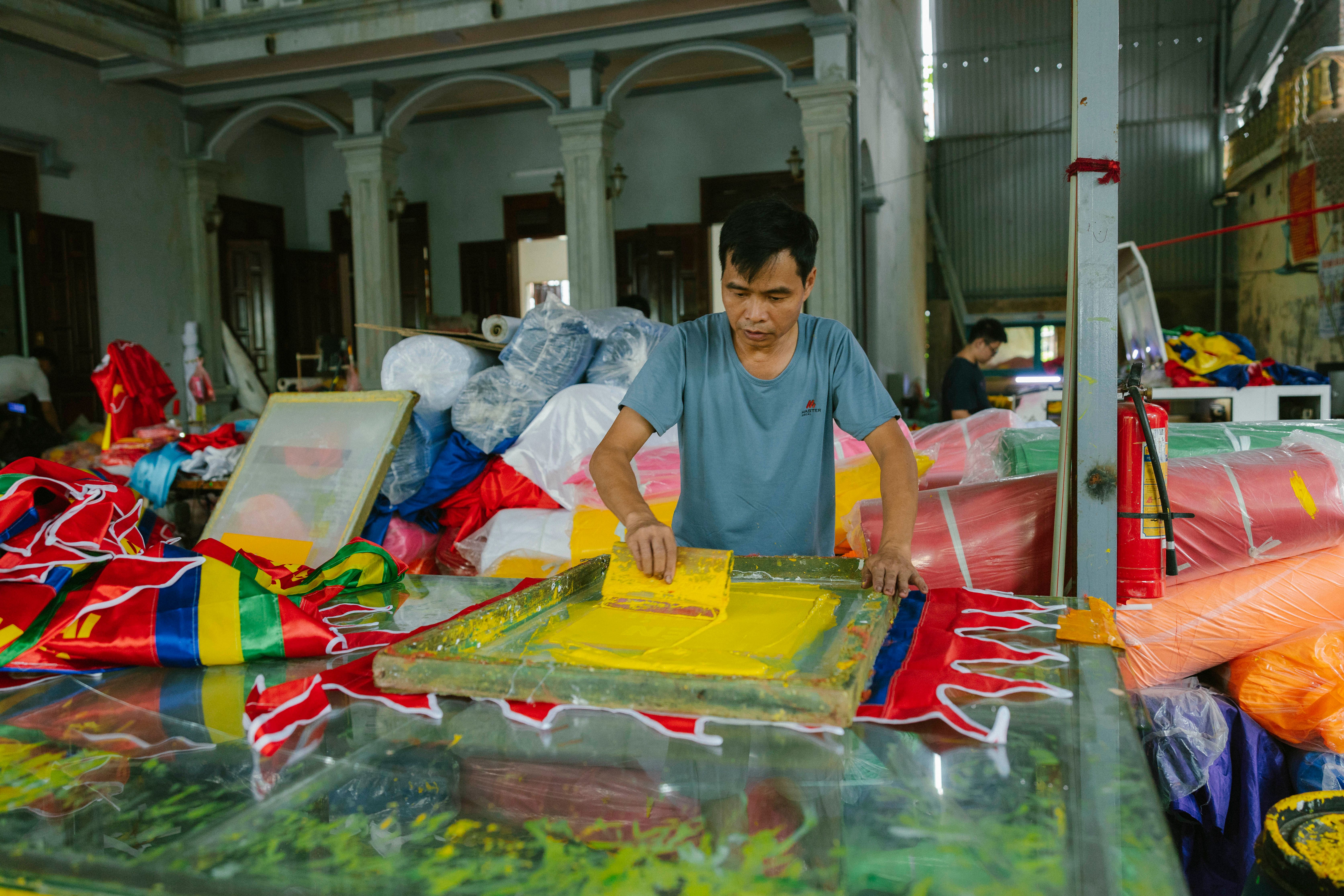 Small-business maker screen printing colorful garments in a workshop