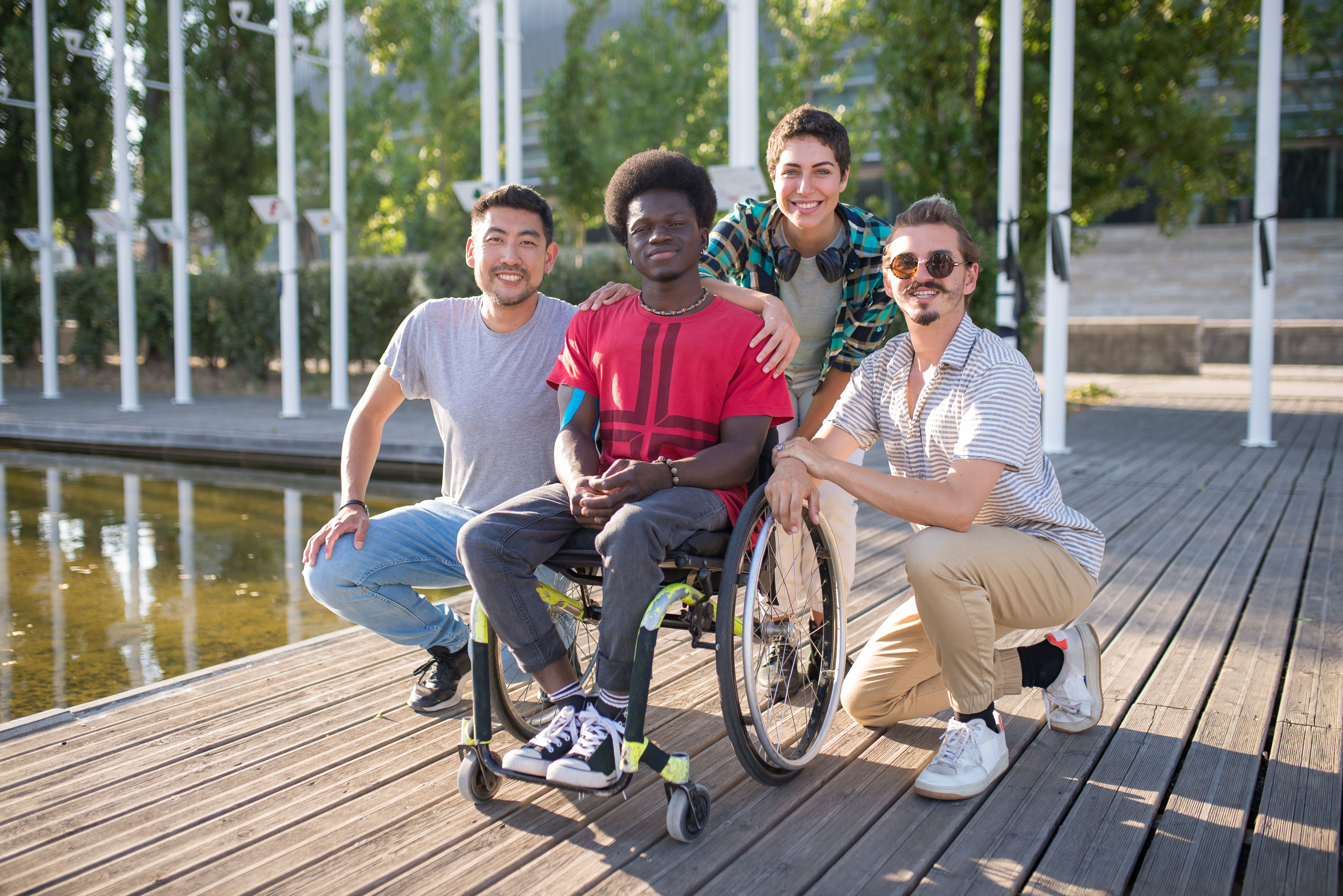 A diverse group of friends, including a wheelchair user, enjoying a sunny day in a park