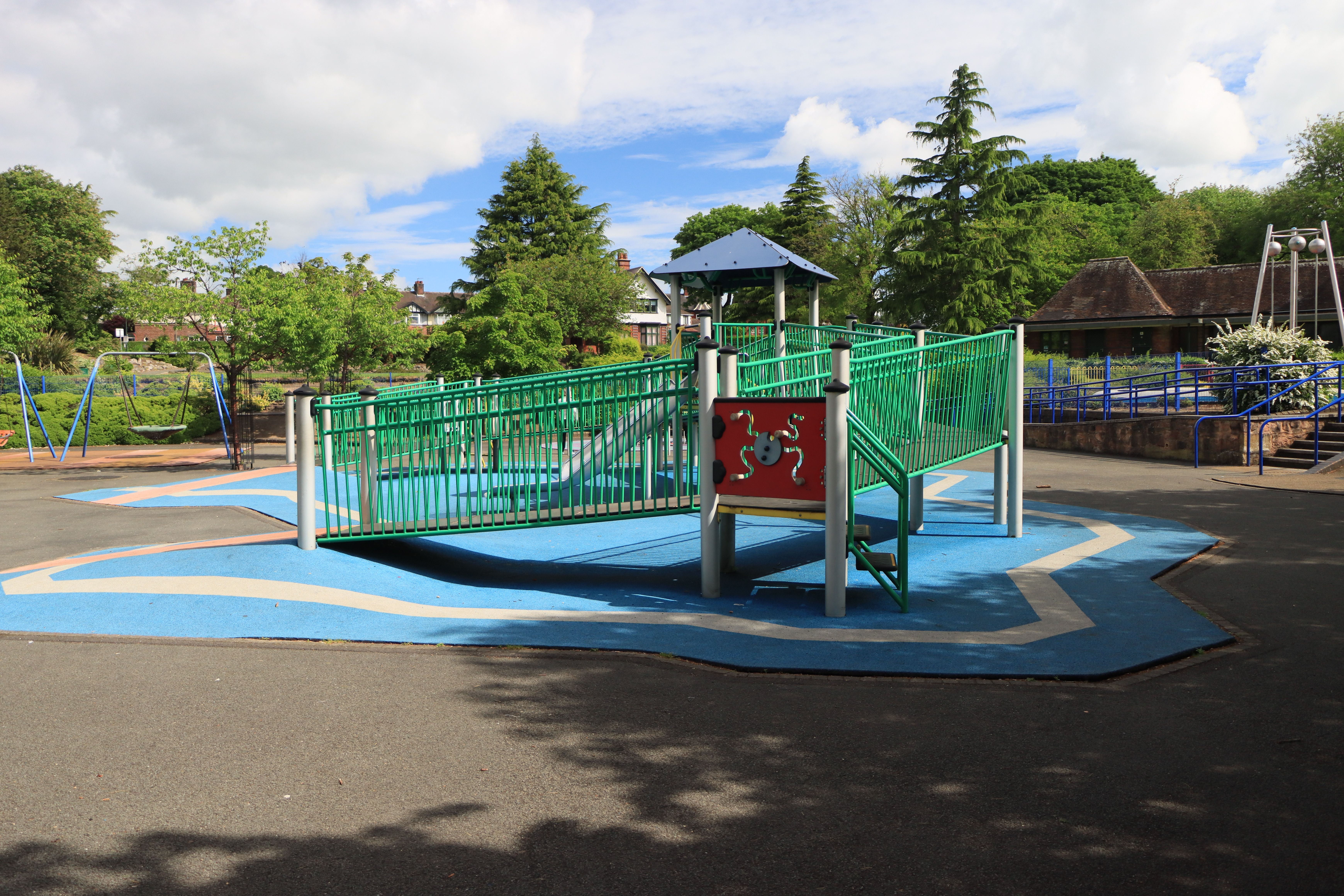 A colorful playground with slides and swings in a sunlit green park