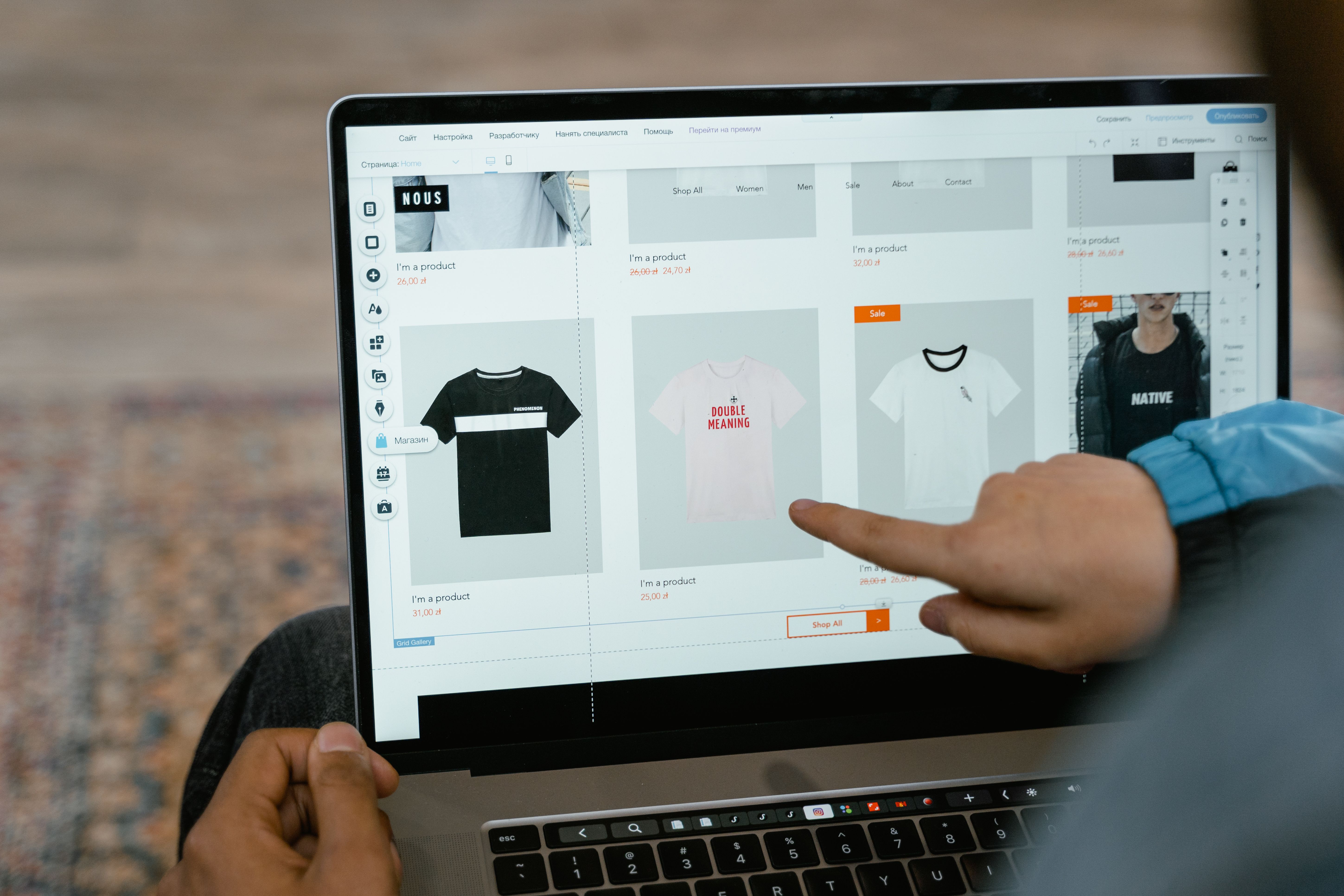 Person browsing T-shirt options in an online store on a laptop